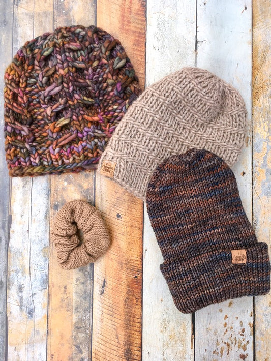 Three brown hats arranged in an arch with a brown scrunchy below the arch