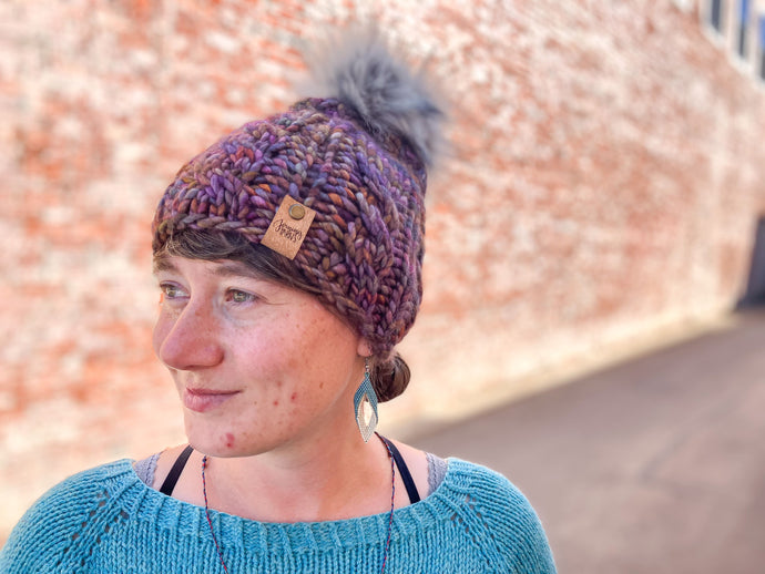 Witch Hazel Beanie in brown with gray pom. It is shown here on a model.