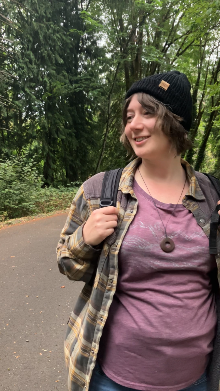 The Hadrosaur Hat is a lightweight, double layered slouchy beanie with folded brim. It is shown here in black on a model on a hiking trail.