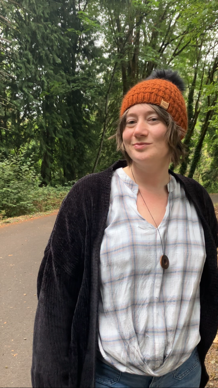 The Messenger Beanie in copper with black pom shown on a model on a hiking trail.