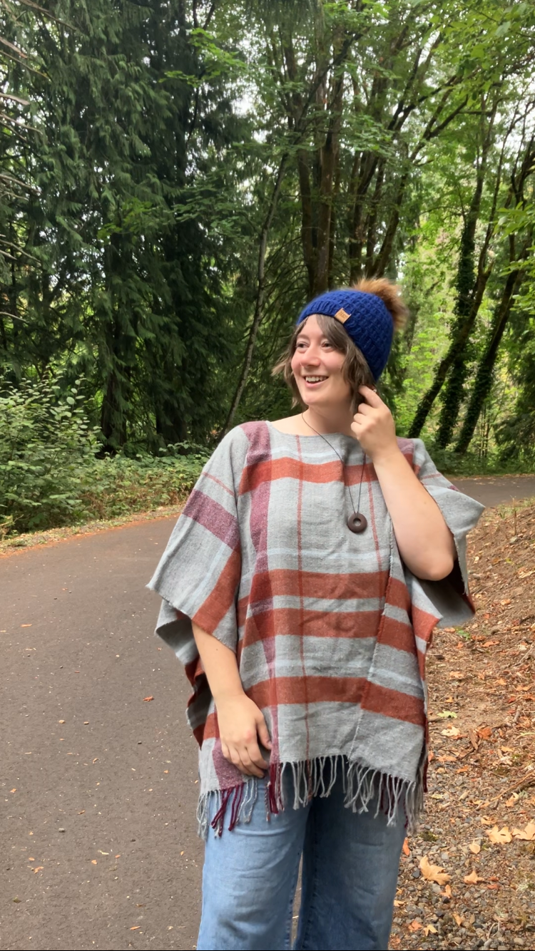 The Messenger Beanie in navy with brown pom shown on a model on a hiking trail.