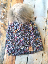 Load image into Gallery viewer, Fossil Beanie in gray with orange and purple speckles with gray pom.  It is shown here in a flat lay.
