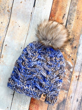 Load image into Gallery viewer, Fossil Beanie in light blue with gray pom.  It is shown here in a flat lay against a wooden background
