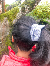 Load image into Gallery viewer, The Cotton Scrunchy is a simple knit hair accessory.  It is show here in gray on a model in a ponytail.
