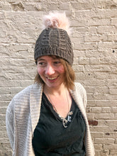 Load image into Gallery viewer, Fossil Beanie in olive with pink pom.  It is shown here on a model.
