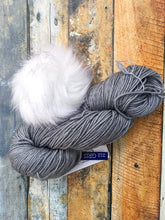 Load image into Gallery viewer, Skein of gray yarn with white pom.

