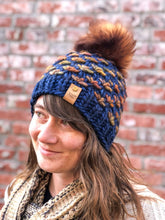 Load image into Gallery viewer, Lotus Beanie in blue with brown flowers and brown pom.  It is shown here on a model.

