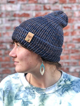 Load image into Gallery viewer, The Hadrosaur Hat is a lightweight, double layered slouchy beanie with folded brim. It is shown here in blue/brown on a model.
