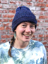 Load image into Gallery viewer, The Hadrosaur Hat is a lightweight, double layered slouchy beanie with folded brim. It is shown here in dark blue/purple on a model.
