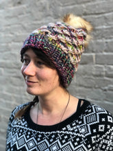 Load image into Gallery viewer, Lotus Beanie in rainbow with beige flowers and white/brown pom.  It is shown here on a model.
