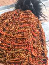 Load image into Gallery viewer, Close up of Fossil Beanie texture in orange with black pom in background.
