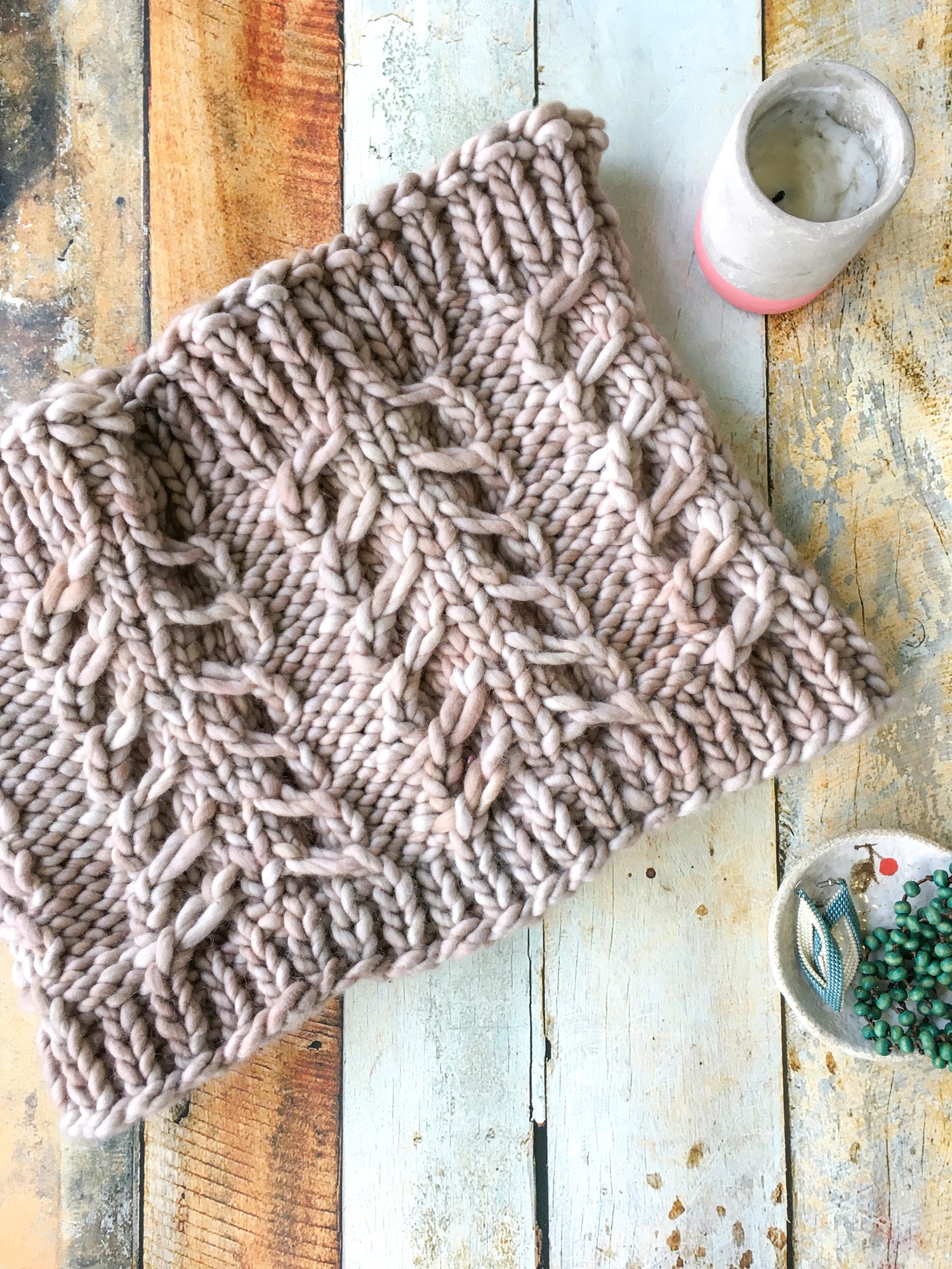 A cream colored Fossil Cowl in a flat lay against a wooden background.