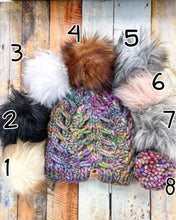 Load image into Gallery viewer, Fossil Beanie in rainbow showing all pom options:  cream, black, white, brown, gray/black, pink, gray, matching yarn.  It is shown in a flat lay against a wooden background.
