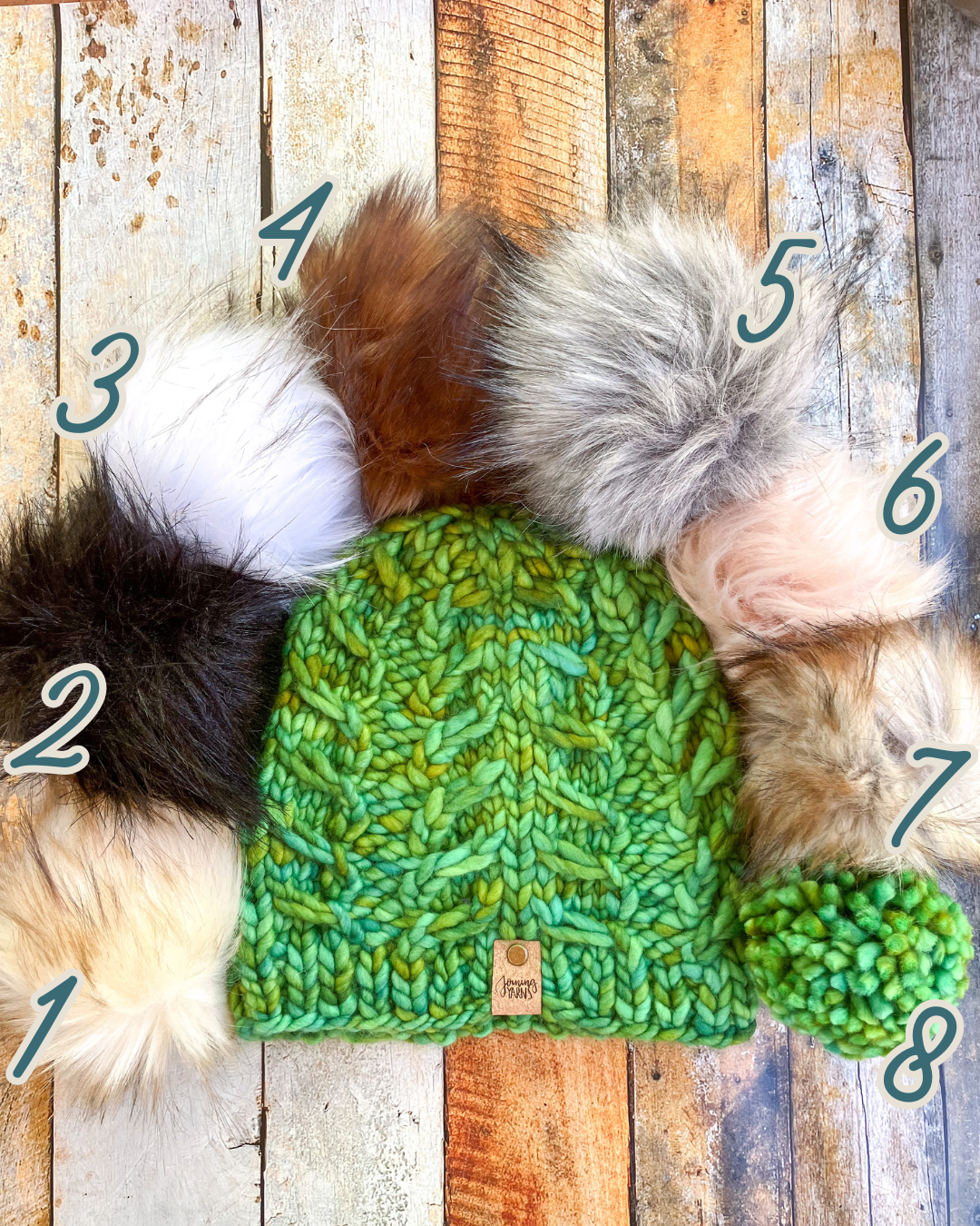 Fossil Beanie in green shown in a flat lay with all 8 pom options.