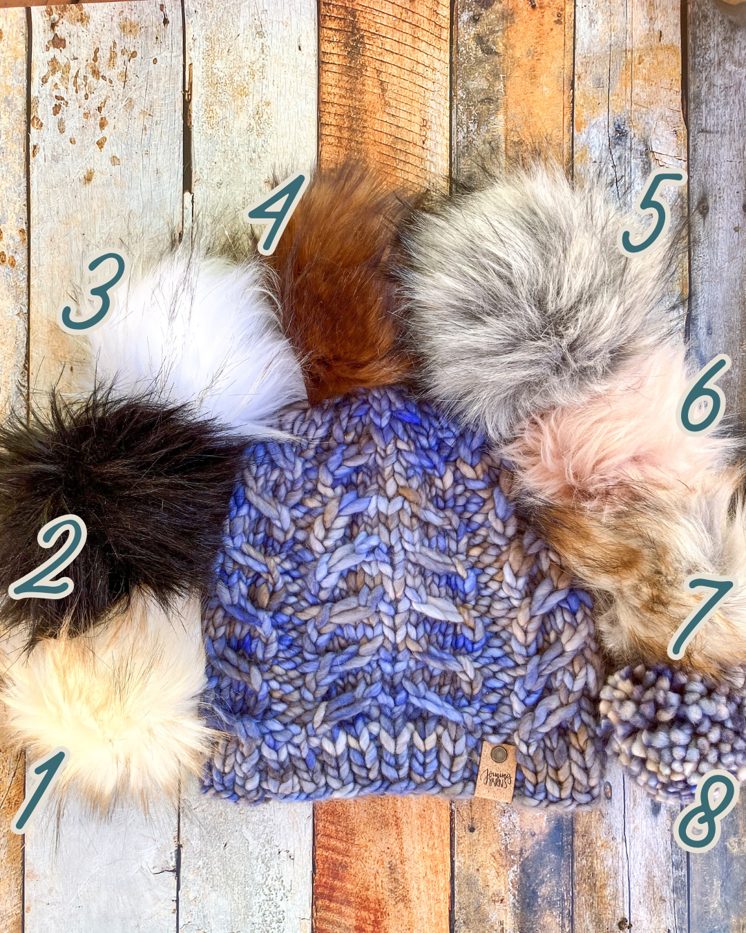Fossil Beanie in light blue and brown shown in a flat lay with all 8 pom options.