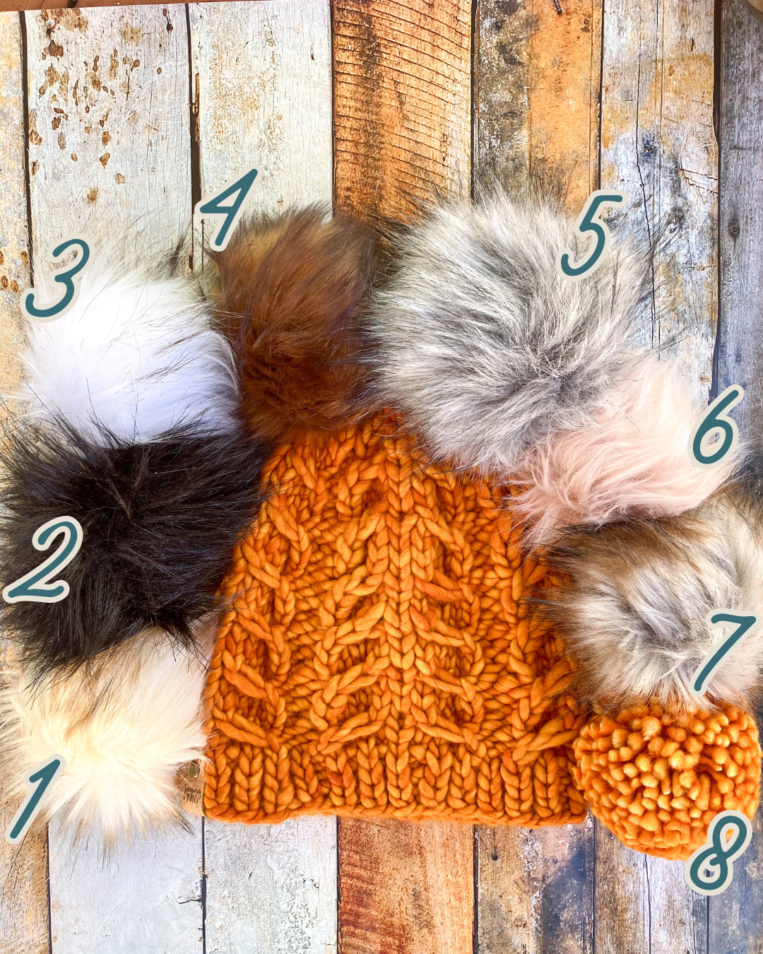 Fossil Beanie in orange shown in a flat lay with all 8 pom options.