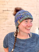 Load image into Gallery viewer, Witch Hazel Beanie in rainbow with brown pom. It is shown here on a model.
