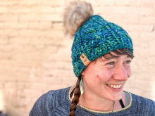 Load image into Gallery viewer, Witch Hazel Beanie in teal with gray pom. It is shown here on a model.
