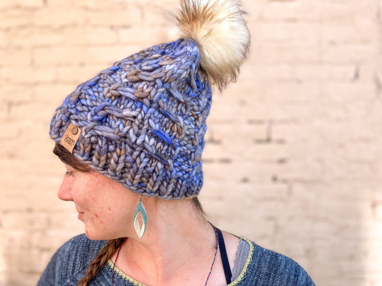 Fossil Beanie in light blue with cream pom.  It is shown here on a model.