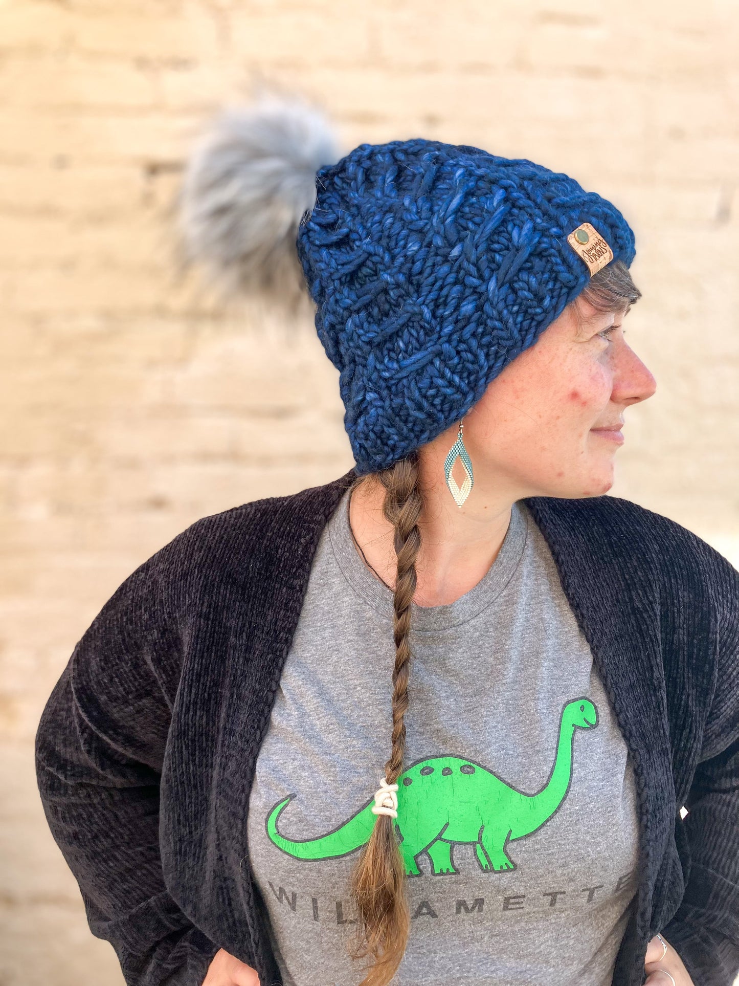 Fossil Beanie in dark blue with gray pom.  It is shown here on a model.
