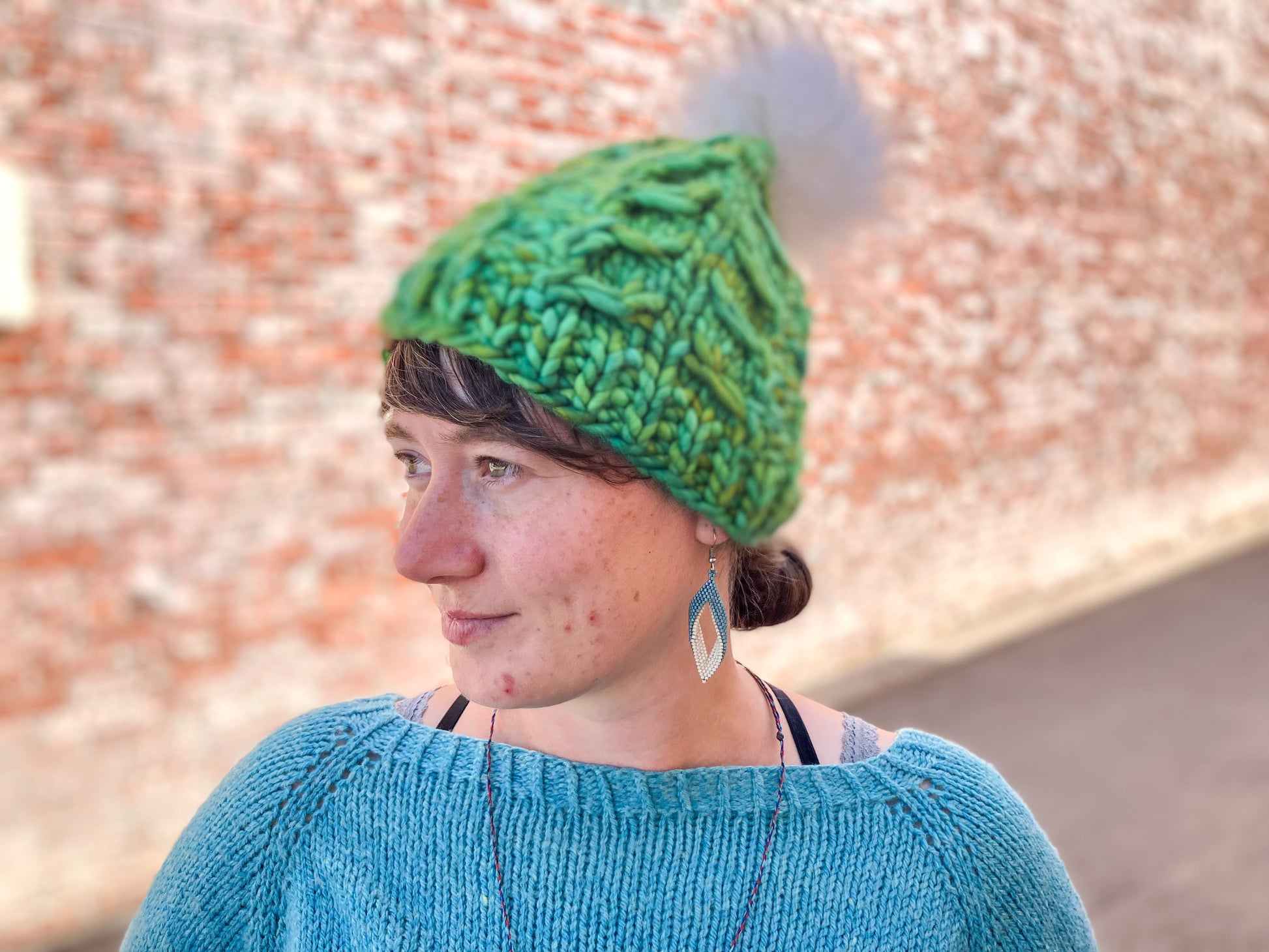 Fossil Beanie in green with white pom.  It is shown here on a model.