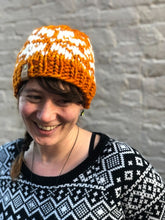 Load image into Gallery viewer, Snowflake Beanie in orange with white snowflake and no pom.  It is shown here on a model.

