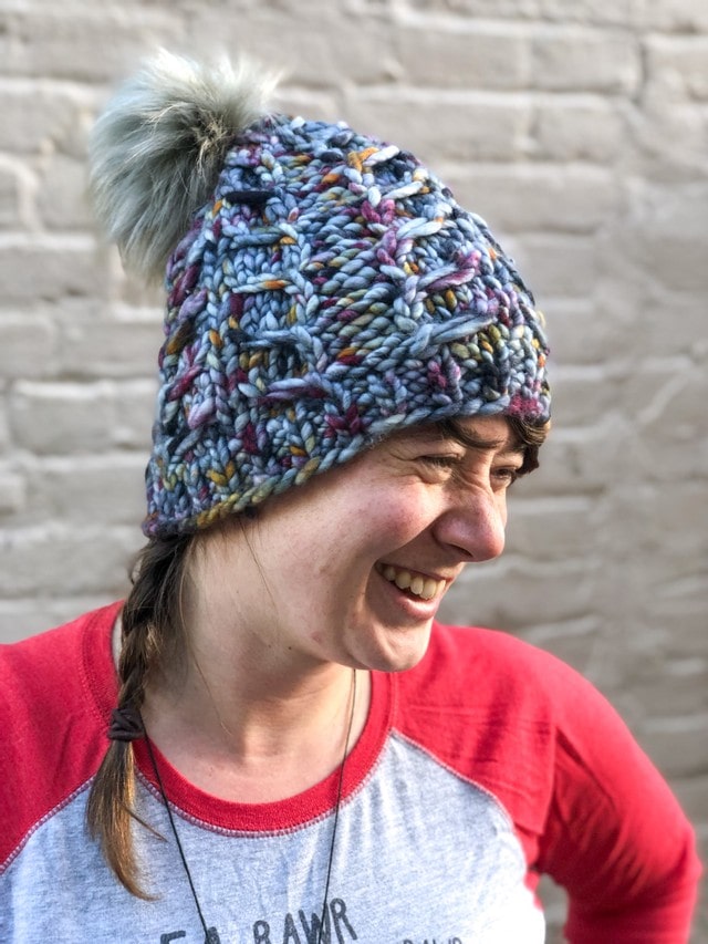 Fossil Beanie in gray with orange and purple speckles with gray pom.  It is shown here on a model.