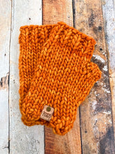 Load image into Gallery viewer, T Rex Mitts in orange in a flat lay against a wooden background.
