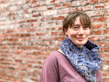 Load image into Gallery viewer, Fossil Cowl in light blue shown on a model wearing a purple shirt against a brick wall
