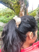 Load image into Gallery viewer, The Cotton Scrunchy is a simple knit hair accessory.  It is show here in light brown (sand) on a model in a ponytail.
