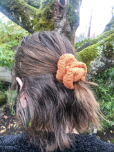Load image into Gallery viewer, The Cotton Scrunchy is a simple knit hair accessory.  It is show here in copper on a model in a half up ponytail..
