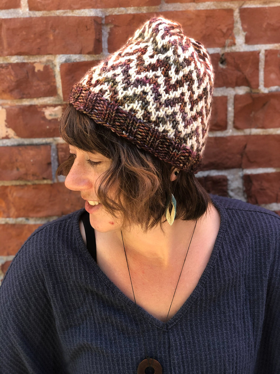 The Find Your Way Beanie has a chevron stripe pattern in two colors.  It is shown here on a model in white and brown.