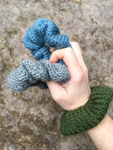Load image into Gallery viewer, Three knit scrunchies are shown in a model&#39;s hands.  They are blue, light gray, and green.
