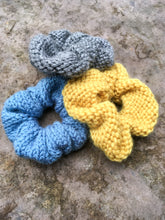 Load image into Gallery viewer, Three knit scrunchies are shown in a flat lay.  They are light gray,  blue, and yellow.
