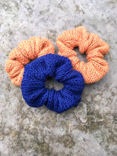 Load image into Gallery viewer, The Cotton Scrunchy is a simple knit hair accessory.  They are shown here in a flat lay in navy and copper.

