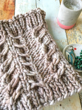 Load image into Gallery viewer, Flat lay of the Fossil Cowl in beige against a wooden background styled with a candle and jewelry dish
