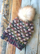 Load image into Gallery viewer, Lotus Beanie in rainbow with beige flowers and white/brown pom.  It is shown here in a flat lay.
