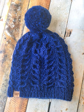 Load image into Gallery viewer, Fossil Beanie in navy with matching yarn pom.  It is shown here in a flat lay.
