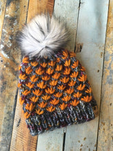 Load image into Gallery viewer, Lotus Beanie in gray with orange flowers and white/black pom. It is shown here in a flat lay.

