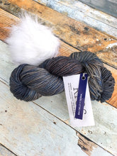 Load image into Gallery viewer, Skein of blue/brown yarn with white pom.
