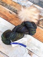 Load image into Gallery viewer, Skein of green/blue yarn with cream pom.
