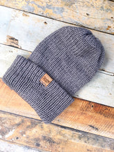 Load image into Gallery viewer, The Hadrosaur Hat is a lightweight, double layered slouchy beanie with folded brim. It is shown here in gray on a model.
