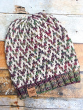 Load image into Gallery viewer, The Find Your Way Beanie has a chevron stripe pattern in two colors.  It is shown here in a flat lay in white and light rainbow.
