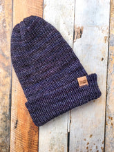 Load image into Gallery viewer, The Hadrosaur Hat is a lightweight, double layered slouchy beanie with folded brim. It is shown here in dark blue/purple in a flat lay.
